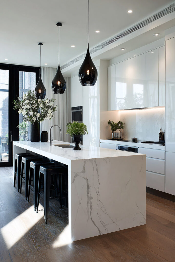 Modern black and white kitchen with white waterfall marble island, black bar stools, glossy white cabinets, black pendant lights, and natural wood floors.