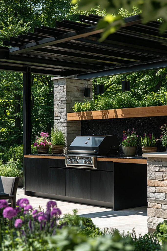 Modern outdoor grill station with black cabinets, built-in stainless steel grill, stone columns, pergola roof, and landscaped backyard.