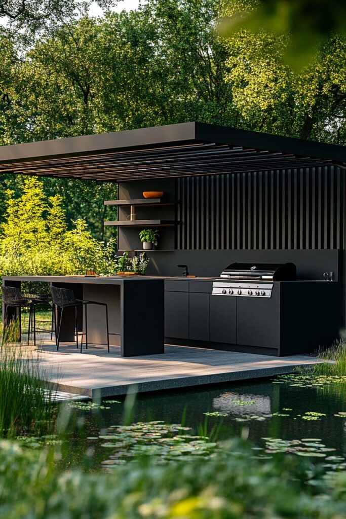Modern outdoor grill station with black cabinets, built-in grill, bar seating, slatted pergola roof, and water feature in a landscaped backyard.