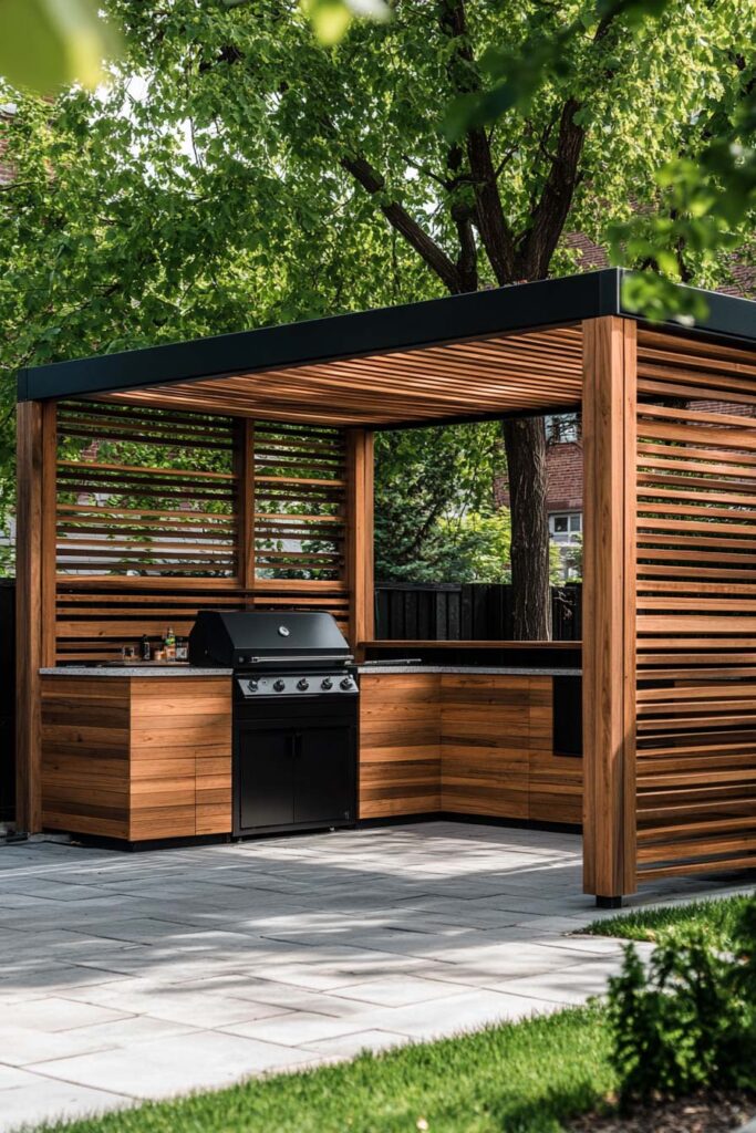 Modern outdoor grill station with wood slat pergola, built-in grill, and L-shaped countertop in a backyard patio.