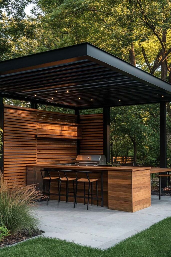 Outdoor grill station with wood bar seating, built-in grill, modern pergola, and warm outdoor lighting.