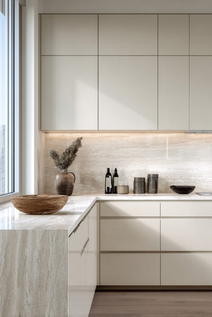 Modern neutral kitchen with smooth cabinetry, dimensional stone backsplash, and textured stone countertop showing layered kitchen surface design.