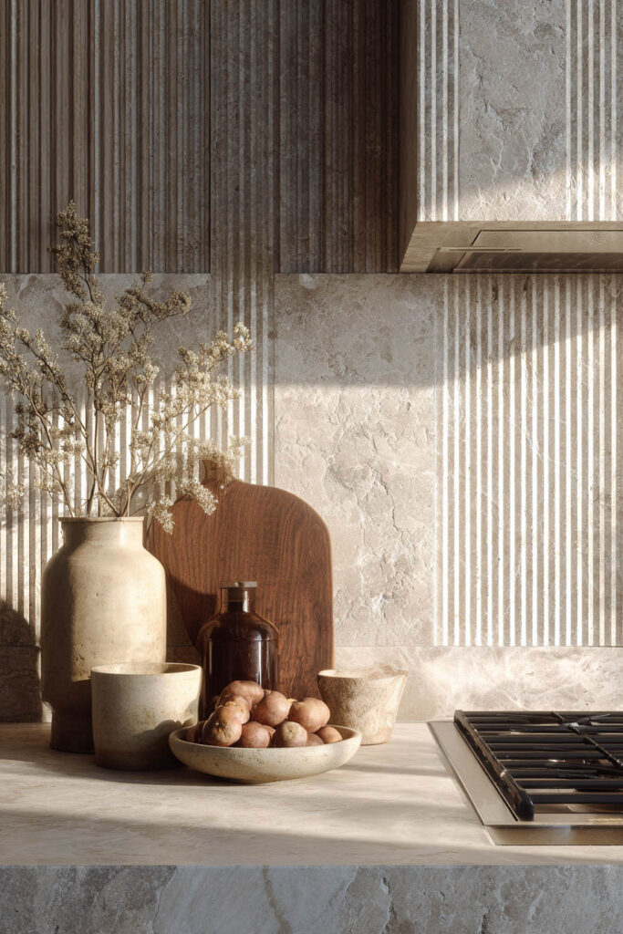 Dimensional kitchen backsplash with ribbed tile and natural stone texture in a warm neutral modern kitchen design