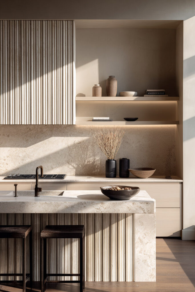 Modern neutral kitchen with fluted island panel and ribbed dimensional surfaces, showcasing textured kitchen design and warm natural materials.