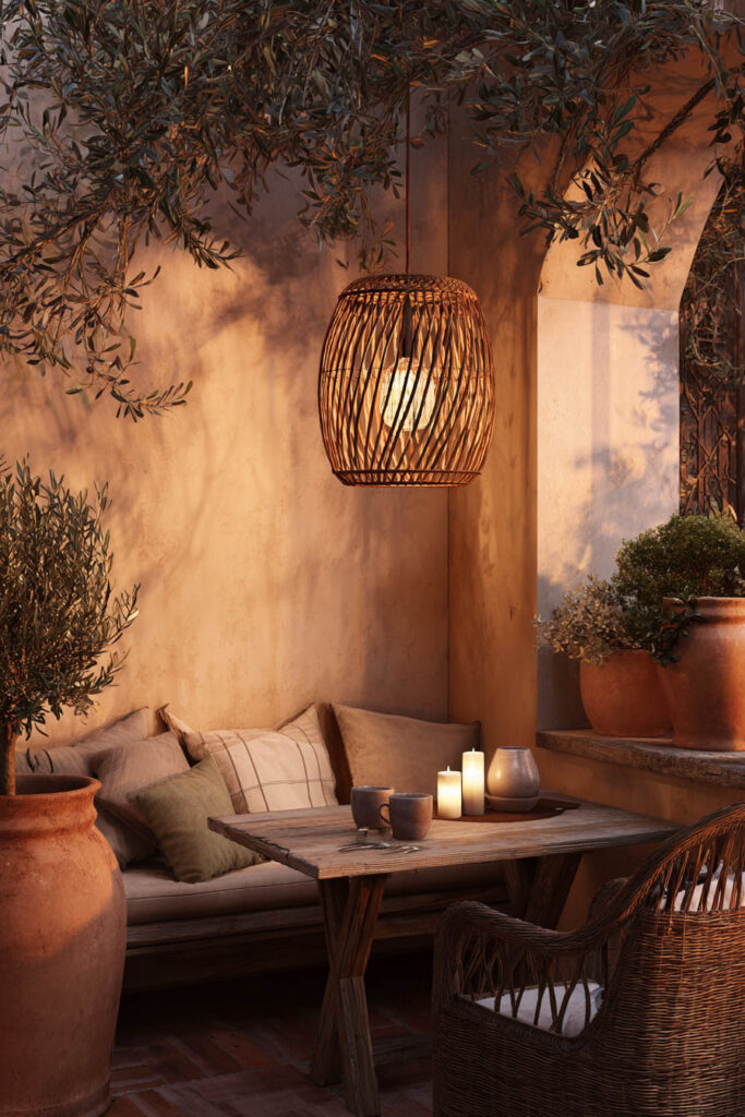 Mediterranean balcony dining nook with woven pendant light, candlelit table, terracotta pots, wicker furniture, and warm evening ambiance.